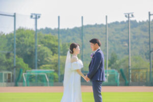 野球場で前撮り　見つめ合う新郎新婦　ウェディングドレスとタキシード