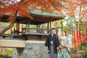 揚輝荘で和装ウェディングフォト　手を繋いで歩く新郎新婦　紅葉の美しい木の下で撮影