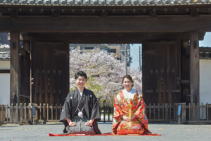 徳川園の黒門前で桜をバックに色打掛の花嫁と正座ショット