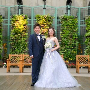 久屋大通庭園フラリエで洋装フォトウェディング　緑をバックに笑顔の新郎新婦　カラードレスとタキシード