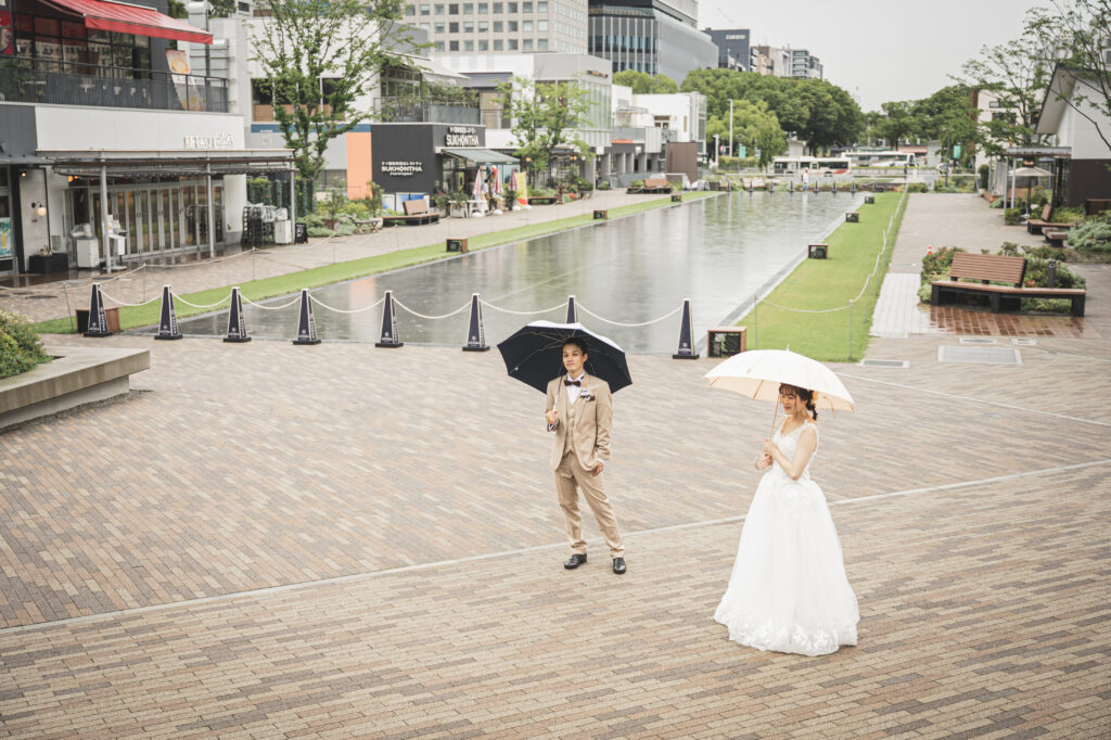 久屋大通パークで傘をさすタキシード姿の新郎とウェディングドレス姿の新婦